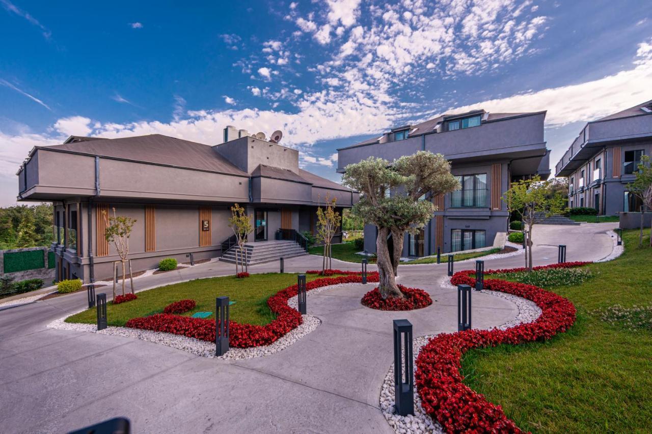 Menalo Hotel Premium Istanbul Airport Екстериор снимка The photo shows a modern architectural setting, featuring two distinct buildings. The first structure is a larger, grey building with a flat roof and multiple levels, while the second building is slightly smaller and has a more angular design. 

In t