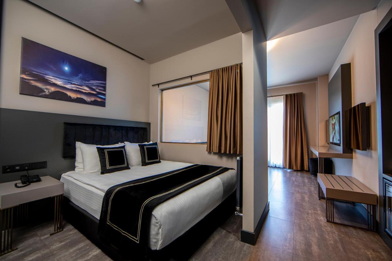 Menalo Hotel Premium Istanbul Airport Екстериор снимка The photo shows a modern hotel room featuring a neatly made bed with white linens and a black decorative runner. There are two pillows with black accents on the bed. The walls are painted in neutral colors, and there is a large window with curtains t
