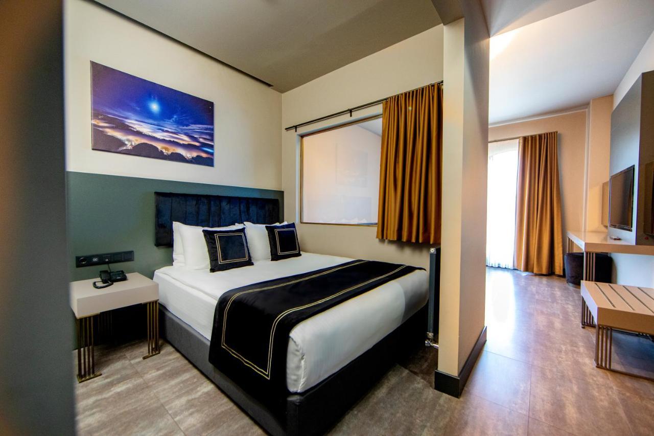Menalo Hotel Premium Istanbul Airport Екстериор снимка The photo shows a modern hotel room featuring a bed with crisp white and black bedding. There are two decorative pillows on the bed, and a piece of art is displayed above it, depicting a scenic landscape with a night sky. The room has a window with n